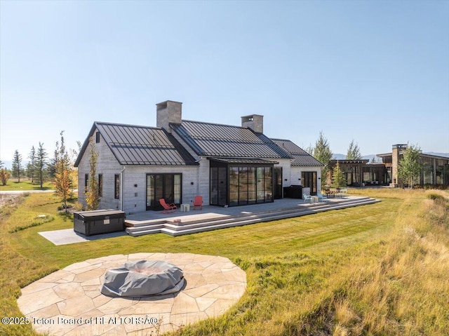 900 Mountain Bluebird Ct, Driggs, ID 83422 - rear view of property featuring a hot tub, an outdoor fire pit, a chimney, a standing seam roof, and a patio area