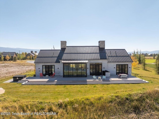 900 Mountain Bluebird Ct, Driggs, ID 83422 - rear view of property with a chimney, a deck with mountain view, a lawn, and a standing seam roof