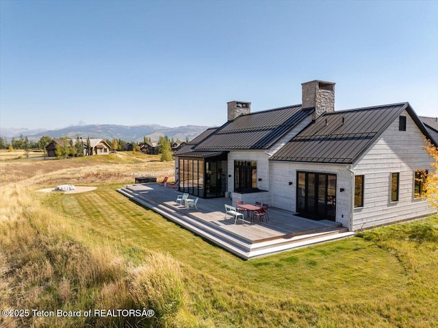 900 Mountain Bluebird Ct, Driggs, ID 83422 - back of property with a standing seam roof, a chimney, a deck with mountain view, a yard, and metal roof