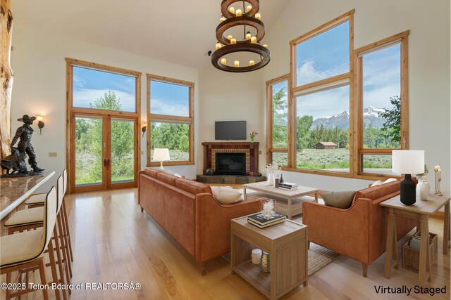 500 E Solitude Dr, Jackson, WY 83001 - living room featuring light wood finished floors, a chandelier, a brick fireplace, a high ceiling, and plenty of natural light