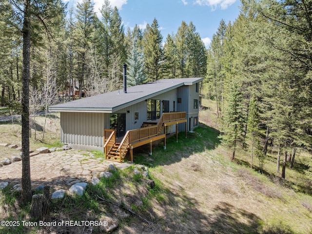 25655 Buffalo Run, Moran, WY 83013 - view of front of house featuring a wooden deck, board and batten siding, a forest view, and stairs