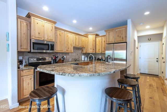 125 Cobble Creek Ln Unit 75, Driggs, ID 83422 - kitchen featuring stainless steel appliances, light brown cabinets, a breakfast bar area, light wood-style flooring, and recessed lighting