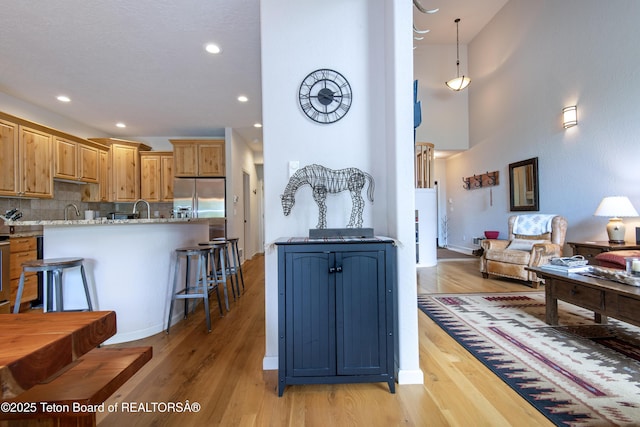 125 Cobble Creek Ln Unit 75, Driggs, ID 83422 - kitchen with stainless steel fridge with ice dispenser, light wood finished floors, tasteful backsplash, a kitchen breakfast bar, and recessed lighting
