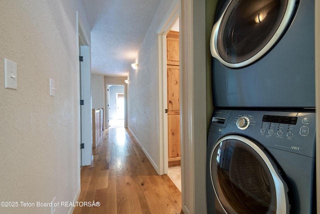 125 Cobble Creek Ln Unit 75, Driggs, ID 83422 - washroom with stacked washer and clothes dryer, light wood-style floors, a textured wall, and baseboards
