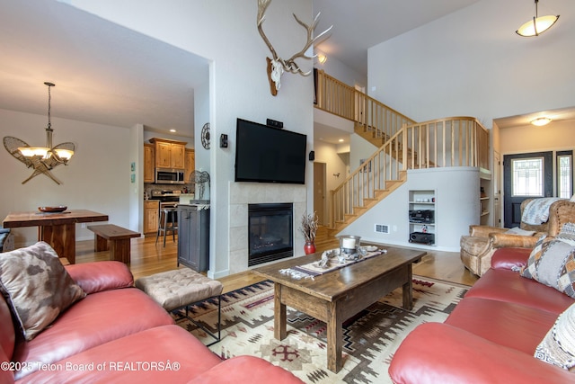 125 Cobble Creek Ln Unit 75, Driggs, ID 83422 - living room featuring light wood-style flooring, a towering ceiling, a chandelier, a fireplace, and stairway