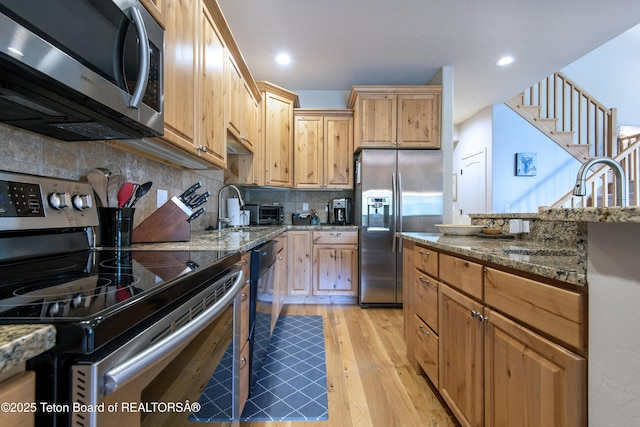 125 Cobble Creek Ln Unit 75, Driggs, ID 83422 - kitchen featuring stainless steel appliances, light wood-style floors, stone countertops, backsplash, and recessed lighting