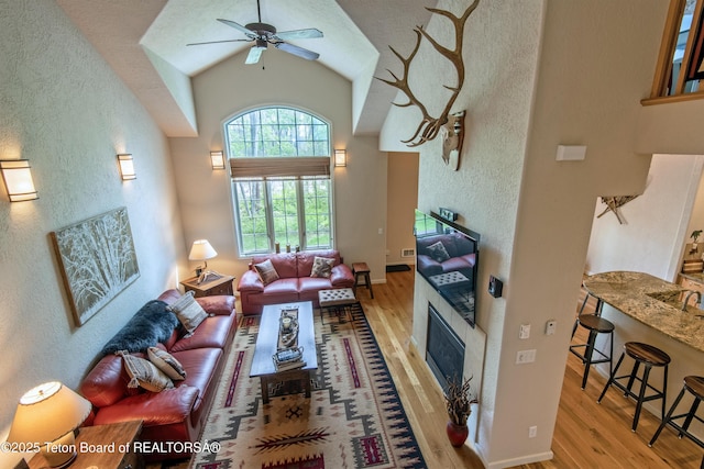 125 Cobble Creek Ln Unit 75, Driggs, ID 83422 - living room with wood finished floors, a glass covered fireplace, ceiling fan, a textured wall, and high vaulted ceiling