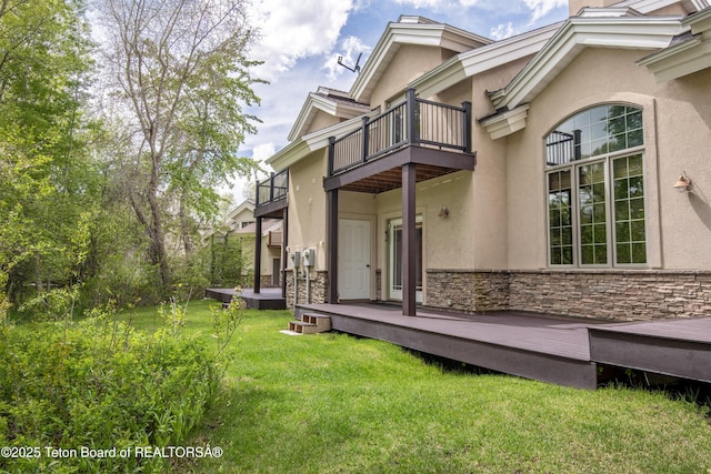 125 Cobble Creek Ln Unit 75, Driggs, ID 83422 - back of house featuring a balcony, stone siding, stucco siding, and a yard