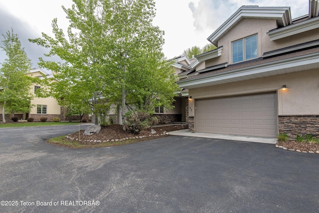 125 Cobble Creek Ln Unit 75, Driggs, ID 83422 - view of front of home with stone siding, stucco siding, asphalt driveway, and a garage