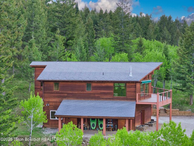 3190 Sorensen Creek Dr, Victor, ID 83455 - back of house featuring a forest view, a shingled roof, and a deck