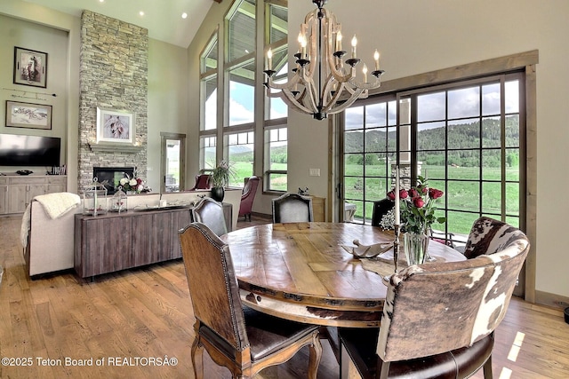 1795 Fumarole Dr, Victor, ID 83455 - dining room featuring a chandelier, light wood finished floors, a fireplace, a towering ceiling, and recessed lighting