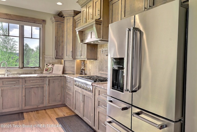 1795 Fumarole Dr, Victor, ID 83455 - kitchen featuring stainless steel appliances, custom range hood, tasteful backsplash, light wood-type flooring, and light stone countertops