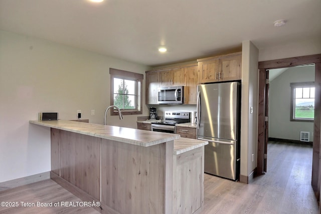 1795 Fumarole Dr, Victor, ID 83455 - kitchen featuring appliances with stainless steel finishes, a peninsula, light wood-style flooring, light countertops, and recessed lighting