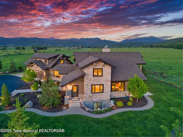 1795 Fumarole Dr, Victor, ID 83455 - view of front facade featuring stone siding, a front yard, a mountain view, and a shingled roof