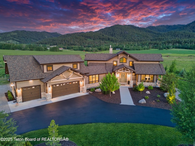 1795 Fumarole Dr, Victor, ID 83455 - view of front of home featuring stone siding, a mountain view, asphalt driveway, and a garage