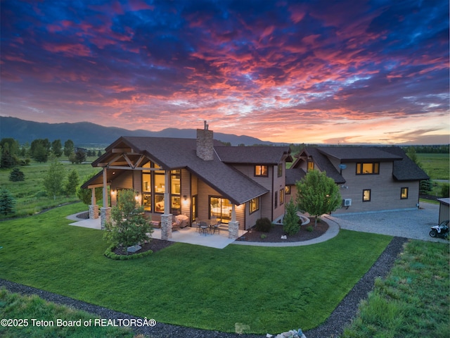 1795 Fumarole Dr, Victor, ID 83455 - back of house featuring a chimney, a lawn, a patio area, and a mountain view