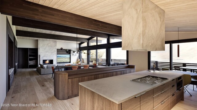 646 Lariat Loop, Jackson, WY 83001 - kitchen with modern cabinets, a wooden ceiling with exposed beams, light wood-style floors, stainless steel gas stovetop, and a fireplace
