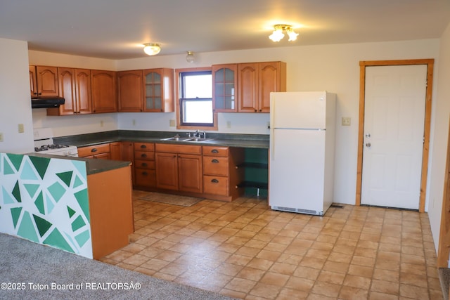 510 Rakestraw Ave, Marbleton, WY 83113 - kitchen with white appliances, brown cabinetry, dark countertops, and under cabinet range hood