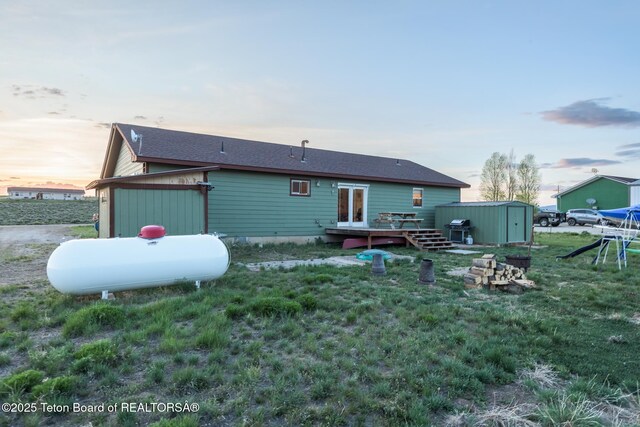 58 Blackhawk Trl, Boulder, WY 82923 - back of house at dusk with a wooden deck and a lawn