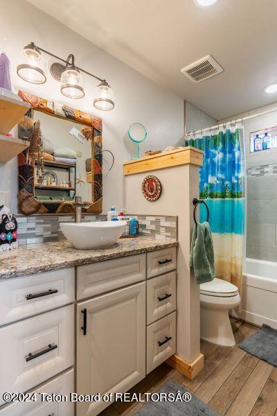 1516 Fischer Ln, Tetonia, ID 83452 - full bathroom with vanity, wood finished floors, toilet, and shower / tub combo with curtain