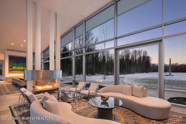 1120 S Thunder Rd, Wilson, WY 83014 - living room with a towering ceiling, a wall of windows, and a lit fireplace