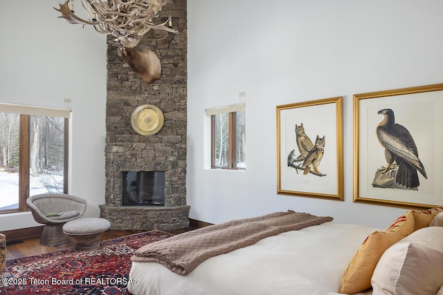 1120 S Thunder Rd, Wilson, WY 83014 - bedroom featuring a fireplace, a towering ceiling, multiple windows, wood finished floors, and a chandelier