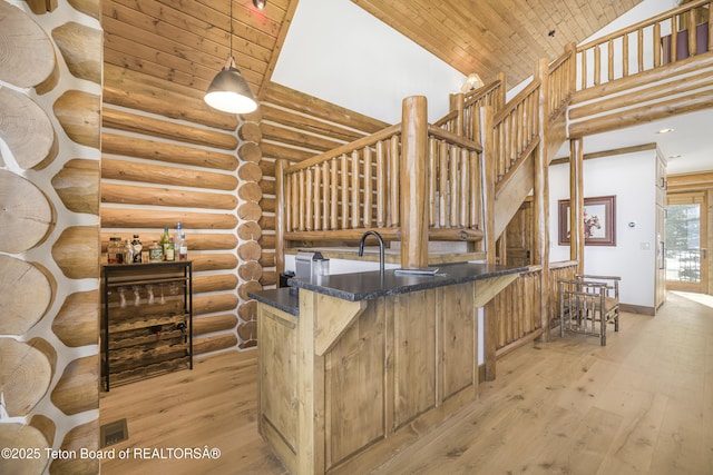 29 Bannock Cir, Victor, ID 83455 - bar area featuring log walls, high vaulted ceiling, wood ceiling, light wood finished floors, and baseboards