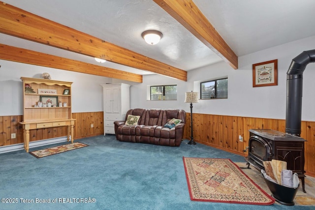 205 Betsy Ct, Bedford, WY 83112 - carpeted living room featuring a wainscoted wall, a wood stove, wood walls, and beam ceiling