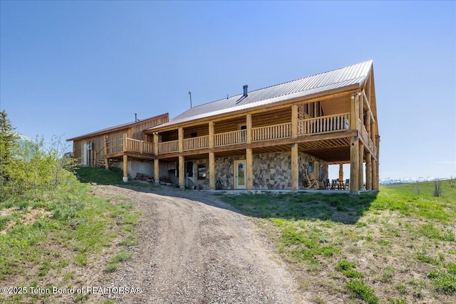 62 Skyline Dr, Bondurant, WY 82922 - rear view of house featuring driveway, metal roof, a wooden deck, and stone siding