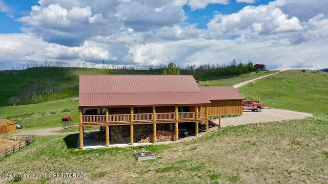 62 Skyline Dr, Bondurant, WY 82922 - rear view of house featuring stone siding, a wooden deck, metal roof, and a rural view