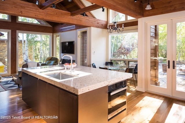 2540 Trader Rd, Jackson, WY 83001 - kitchen featuring open floor plan, wood finished floors, light stone countertops, stainless steel oven, and french doors