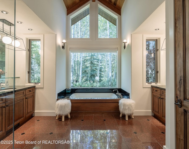 2540 Trader Rd, Jackson, WY 83001 - bathroom with vanity, granite tiled floors, a garden tub, and high vaulted ceiling