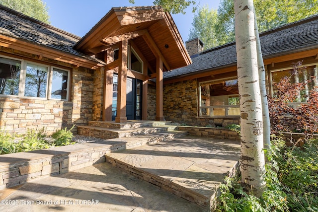 2540 Trader Rd, Jackson, WY 83001 - view of exterior entry featuring stone siding, a chimney, and a patio area