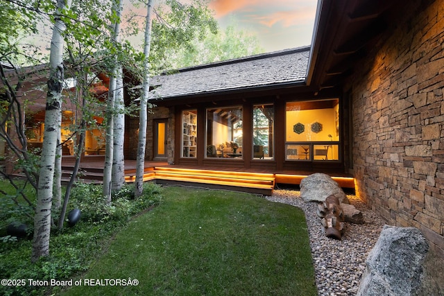 2540 Trader Rd, Jackson, WY 83001 - back of house at dusk with a yard, a wooden deck, and stone siding