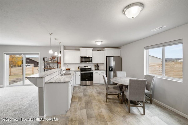 365 Little Greys Lp, Etna, WY 83118 - kitchen featuring stainless steel appliances, a peninsula, healthy amount of natural light, and light stone countertops