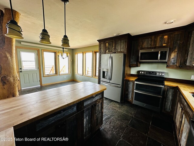 21 Hawk Path, Boulder, WY 82923 - kitchen featuring butcher block counters, appliances with stainless steel finishes, hanging light fixtures, stone tile floors, and dark brown cabinetry