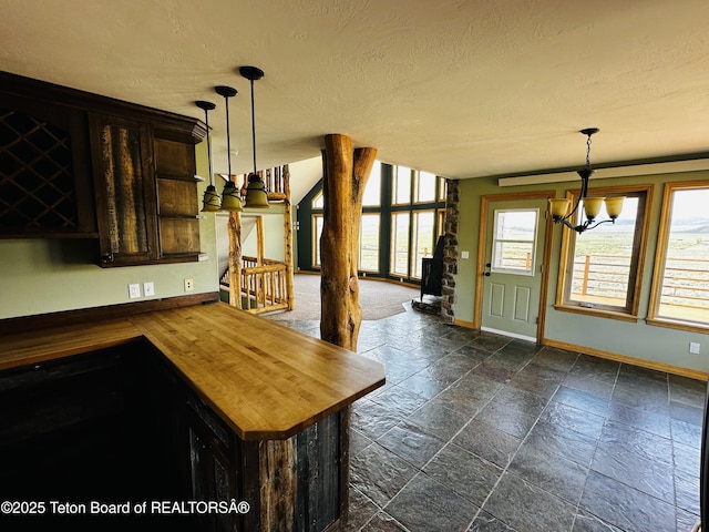 21 Hawk Path, Boulder, WY 82923 - kitchen featuring butcher block countertops, a chandelier, baseboards, stone tile flooring, and a textured ceiling