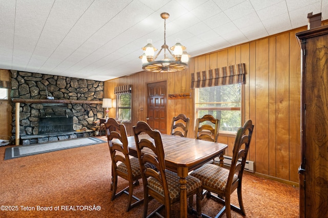 739 Pinecrest, Alpine, WY 83128 - dining space with carpet, a baseboard heating unit, a chandelier, wood walls, and a fireplace