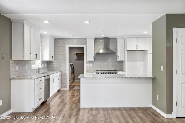560 Appaloosa Trl, Driggs, ID 83422 - kitchen with wall chimney range hood, washing machine and clothes dryer, a sink, stainless steel dishwasher, and backsplash