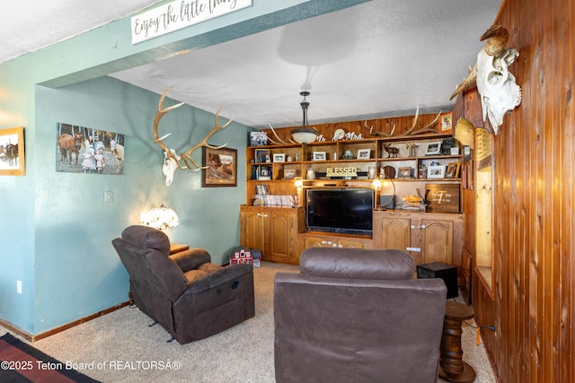 105 Heap Dr, Thayne, WY 83127 - carpeted living area featuring a textured ceiling, wooden walls, and baseboards