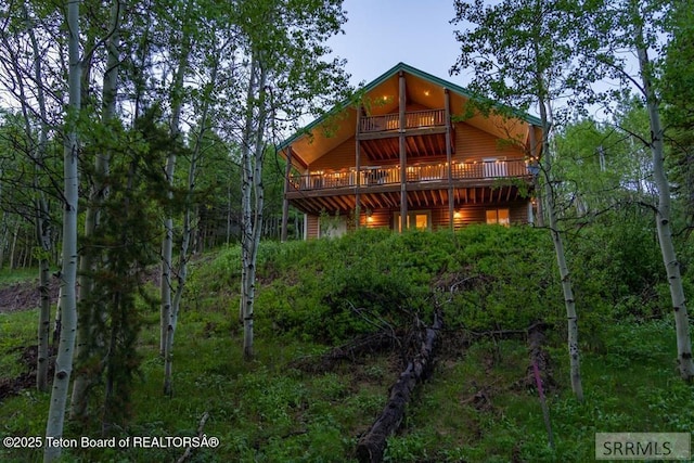 4770 Deer Dr, Island Park, ID 83429 - rear view of house featuring log veneer siding, a deck, and a view of trees