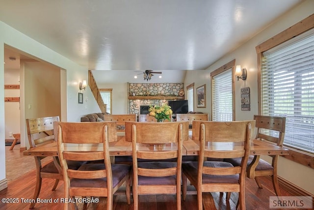 4770 Deer Dr, Island Park, ID 83429 - dining room with a stone fireplace, ceiling fan, light wood-style flooring, and baseboards