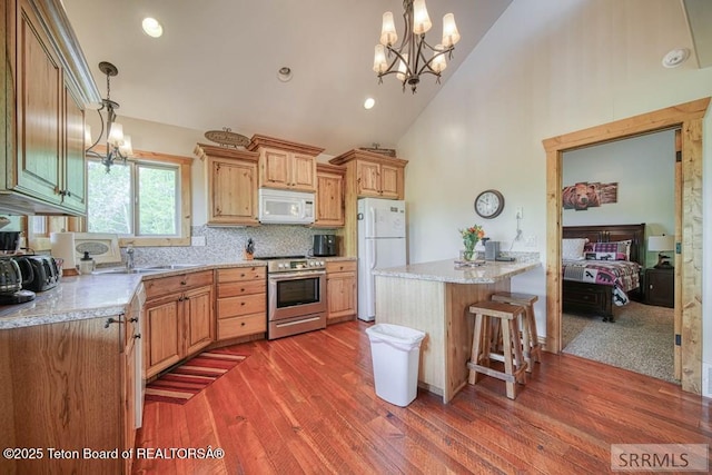 4770 Deer Dr, Island Park, ID 83429 - kitchen with white appliances, wood finished floors, light countertops, a chandelier, and tasteful backsplash