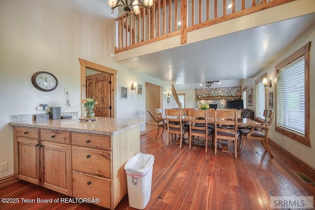 4770 Deer Dr, Island Park, ID 83429 - dining space featuring dark wood finished floors, a towering ceiling, a stone fireplace, and baseboards