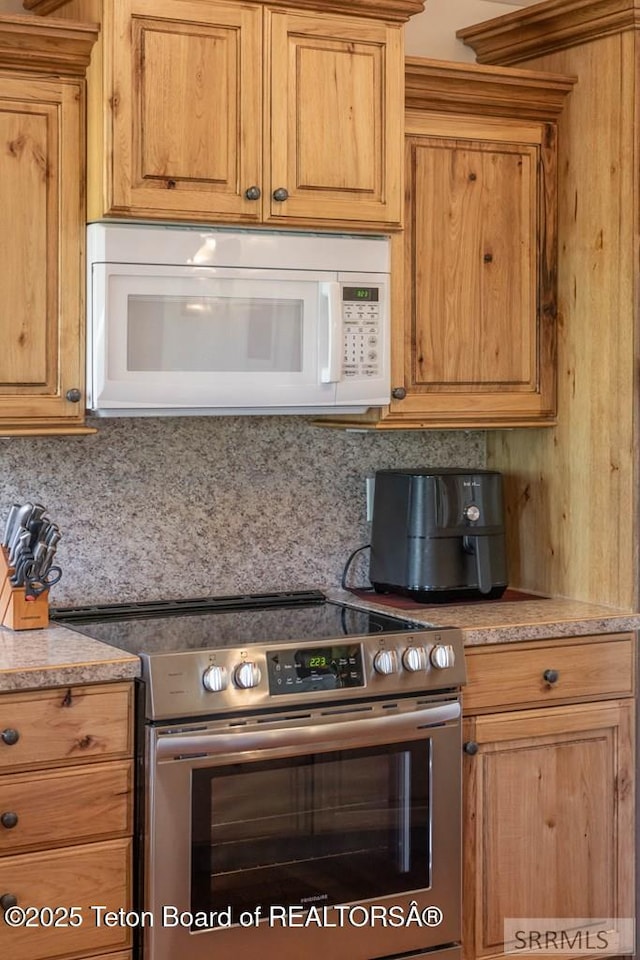 4770 Deer Dr, Island Park, ID 83429 - kitchen featuring stainless steel range with electric cooktop, white microwave, and backsplash