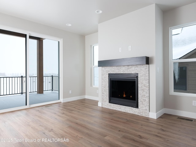 311 Bald Eagle Dr, Victor, ID 83455 - unfurnished living room featuring a stone fireplace, wood finished floors, baseboards, and plenty of natural light