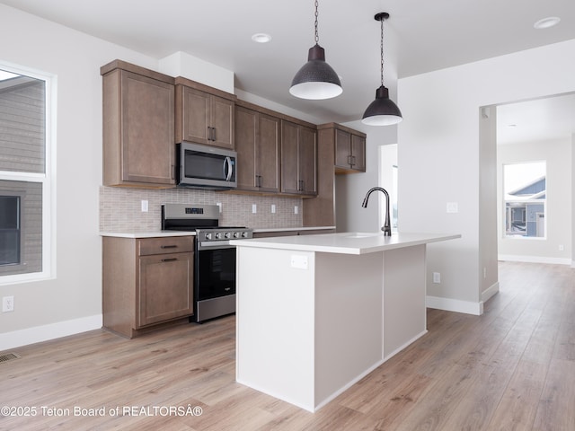 311 Bald Eagle Dr, Victor, ID 83455 - kitchen with stainless steel appliances, decorative backsplash, light wood-style floors, and light countertops