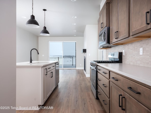 311 Bald Eagle Dr, Victor, ID 83455 - kitchen with appliances with stainless steel finishes, a sink, light wood-type flooring, backsplash, and light countertops