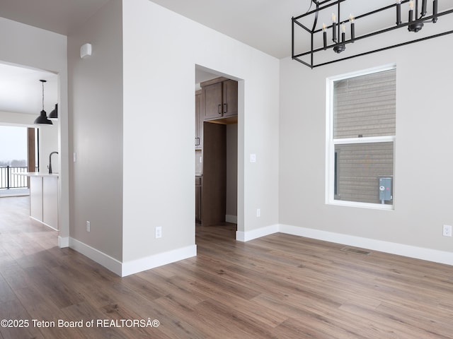 311 Bald Eagle Dr, Victor, ID 83455 - empty room with wood finished floors, a chandelier, and baseboards