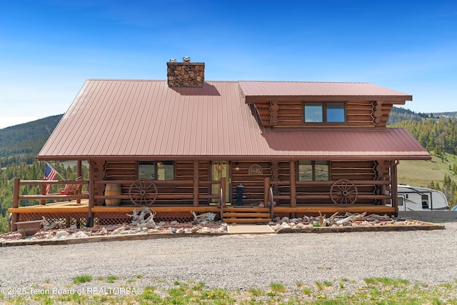 196 Soda Springs Dr, Dubois, WY 82513 - log home featuring log exterior, covered porch, a chimney, a metal roof, and a mountain view